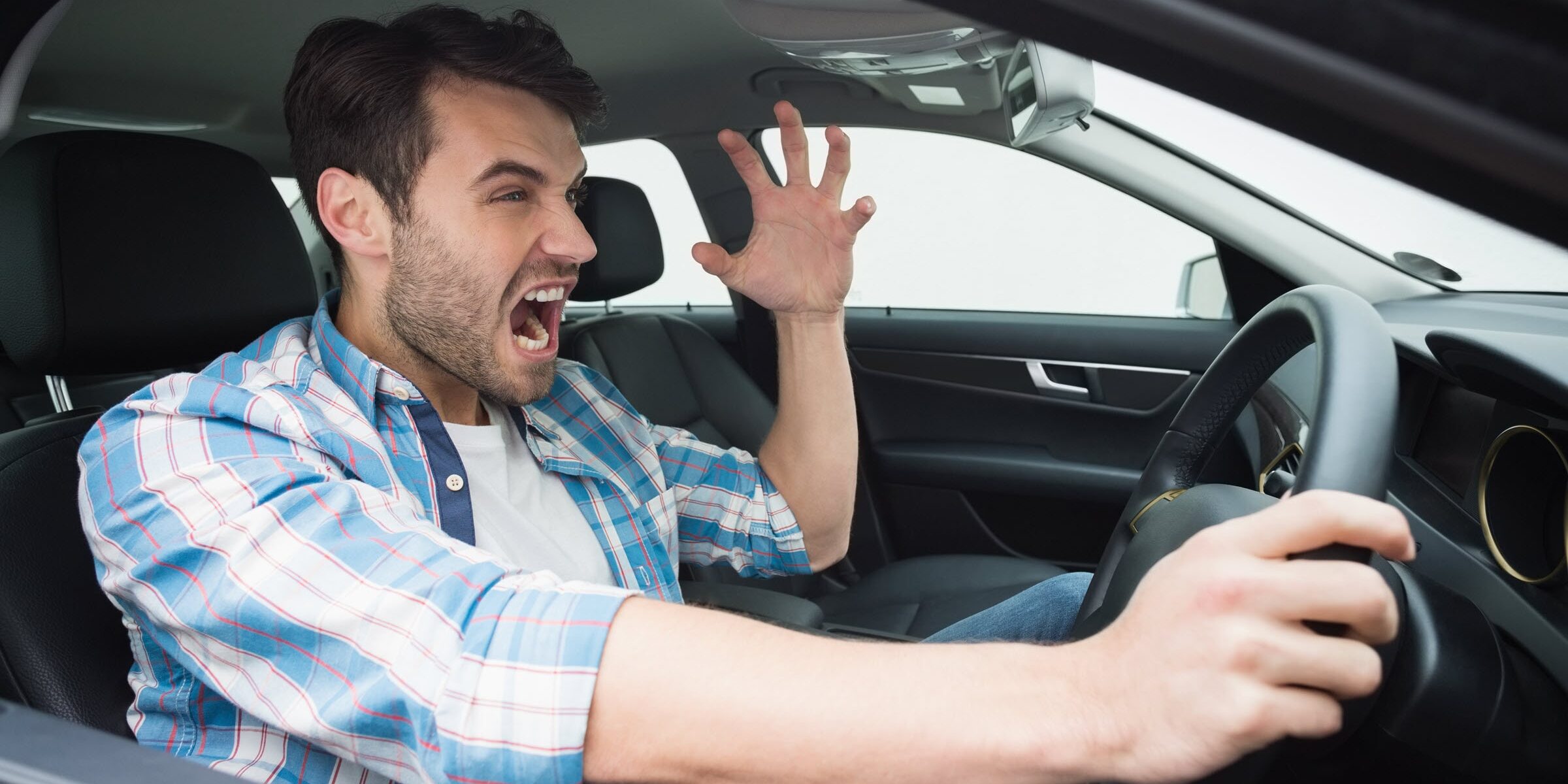 Man experiencing road rage in car.